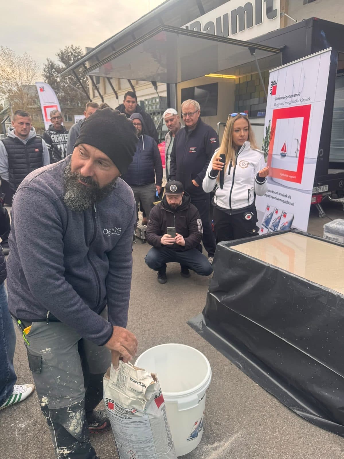 Ragasztó keverése a bemutatón, a háttérben a Baumit Roadshow stand